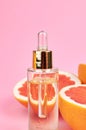 Bottle with pure grapefruit essential oil on grapefruit halves. Aromatherapy treatment concept.
