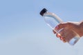 Bottle with water in hand on the background of the sea