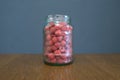 Red ripe fresh raspberry berry in a glass jar on a wooden table.