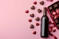 Bottle of red wine with box of chocolate candies on pink background Royalty Free Stock Photo