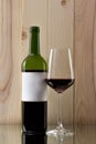 Bottle of red wine with a brilliant glass on a wooden background on a glass stand