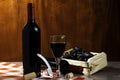 Bottle of red wine in wine cellar for tasting. Red wooden background with wooden box with grapes. Wine tradition and culture conce Royalty Free Stock Photo