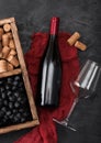 Bottle of red wine on red cloth with empty glass and dark grapes with corks and corkscrew inside vintage wooden box on dark wooden Royalty Free Stock Photo