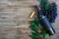 Bottle with red wine, corkscrew, blue grapes, leaves on a wooden table. Wine background with copy space. Top view, flat lay Royalty Free Stock Photo