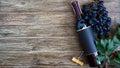 Bottle with red wine, corkscrew, blue grapes, leaves on a wooden table. Wine background with copy space. Top view, flat lay Royalty Free Stock Photo