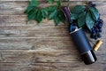 Bottle with red wine, corkscrew, blue grapes, leaves on a wooden table. Wine background with copy space. Top view, flat lay Royalty Free Stock Photo