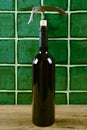 Bottle of red wine with corkscrew over green background. Royalty Free Stock Photo