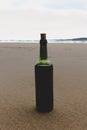 Bottle of red wine on empty beach. Homemade wine in green glass bottle. Full bottle of red wine with cork. Vacation on seacoast. Royalty Free Stock Photo