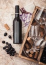 Bottle of red wine and empty glass with dark grapes with corks and opener inside vintage wooden box on wooden background with Royalty Free Stock Photo