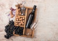 Bottle of red wine and empty glass with dark grapes with corks and opener inside vintage wooden box on wooden background with Royalty Free Stock Photo