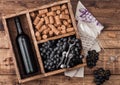 Bottle of red wine and empty glass with dark grapes with corks and opener inside vintage wooden box on grunge wooden background Royalty Free Stock Photo