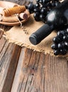 Bottle of red wine with fresh grape and bunch of corks on wooden table Royalty Free Stock Photo