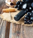 Bottle of red wine with fresh grape and bunch of corks on wooden table Royalty Free Stock Photo