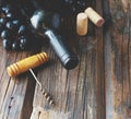 Bottle of red wine with fresh grape and bunch of corks on wooden table Royalty Free Stock Photo