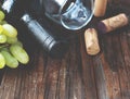 Bottle of red wine with fresh grape and bunch of corks on wooden table Royalty Free Stock Photo