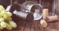 Bottle of red wine with fresh grape and bunch of corks on wooden table Royalty Free Stock Photo