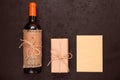 Bottle of red wine, gift box wrapped in kraft paper and blank greeting card on black background. Zero waste holidays Royalty Free Stock Photo