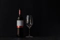 A bottle of red wine and a glass on a black background. Royalty Free Stock Photo