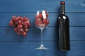 Bottle of red wine, glass and grapes on blue wooden table, flat lay Royalty Free Stock Photo