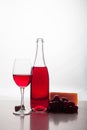 a bottle of red wine, a glass, grapes and cheese on a white table Royalty Free Stock Photo