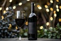 Bottle of red wine and glass of wine on table with blurred background of garland Royalty Free Stock Photo