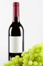 Bottle of red wine and green grapes in front Royalty Free Stock Photo