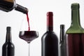 Bottle of red wine poured into the wine glass, and variety of wine bottles with selective focus on  white background Royalty Free Stock Photo