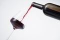 Bottle of red wine poured into the wine glass, on white background