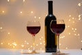 A bottle of red wine on the right side of the photo and two full glasses, with bokeh in the background. Royalty Free Stock Photo