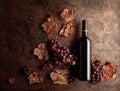 Bottle of red wine with ripe grapes and dried up vine leaves. Old copper background Royalty Free Stock Photo