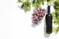 Bottle of red wine with ripe grapes and vine leaves on white background. Royalty Free Stock Photo