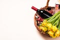 Bottle of red wine, tulip flowers and cosmetic in gift basket Royalty Free Stock Photo