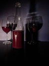 A bottle of red wine and two glasses stands on a black surface, against a background of an abstract blue wall. Royalty Free Stock Photo