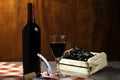 Bottle of red wine in wine cellar for tasting. Red wooden background with wooden box with grapes. Wine tradition and culture conce Royalty Free Stock Photo