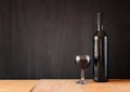 Bottle of red wine and wine glass over wooden table. image is filtered, instagram style