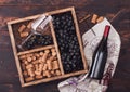 Bottle of red wine on wood with empty glass with dark grapes with corks and corkscrew inside vintage wooden box on dark wooden Royalty Free Stock Photo