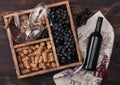 Bottle of red wine on wood with empty glasses with dark grapes with corks and corkscrew inside vintage wooden box on dark wooden Royalty Free Stock Photo