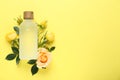 Bottle of rose essential oil and beautiful flowers on pale yellow background, top view. Space for text Royalty Free Stock Photo