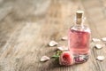 Bottle of rose essential oil and flower on wooden table Royalty Free Stock Photo