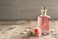 Bottle of rose essential oil and flower on wooden table Royalty Free Stock Photo