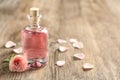 Bottle of rose essential oil and flower on wooden table Royalty Free Stock Photo