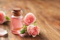 Bottle of rose essential oil and flowers on wooden table, space for Royalty Free Stock Photo