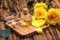 Bottle of rose essential oil and flowers on wooden table, space for text Royalty Free Stock Photo