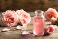 Bottle of rose essential oil and flowers on wooden table Royalty Free Stock Photo