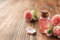 Bottle of rose essential oil and flowers on wooden table Royalty Free Stock Photo