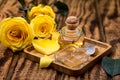 Bottle of rose essential oil and flowers on wooden table, space for text Royalty Free Stock Photo