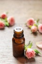 Bottle of rose essential oil and fresh flowers on wooden table Royalty Free Stock Photo