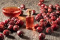 A bottle of rose hip seed oil with dried rose hips on a table Royalty Free Stock Photo