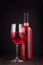 Bottle of rose wine and wine glass mock up on elegant dark black wooden background, vertical. Royalty Free Stock Photo