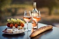 Bottle of rose wine and two full glasses of wine on table in heart of Provence, France with french bread, cheese, ham, grapes and Royalty Free Stock Photo